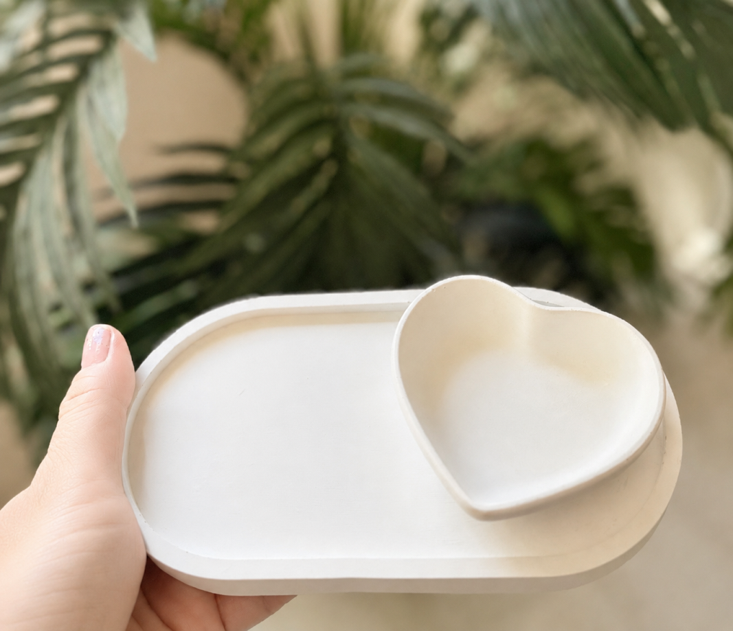 Mão segurando bandeja oval com porta-joias em formato de coração